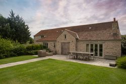 Rustic stone house with red-tiled roof and outdoor patio furniture