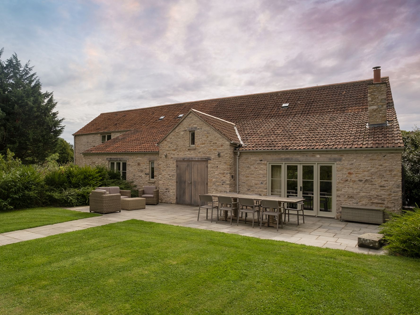 Rustic stone house with red-tiled roof and outdoor patio furniture