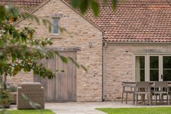 Stone house with patio furniture and a wooden door
