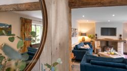 Cozy living room with blue sofas, a fireplace, and a large wall mirror reflecting the room