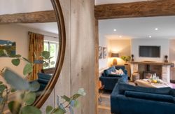 Cozy living room with blue sofas, a fireplace, and a large wall mirror reflecting the room