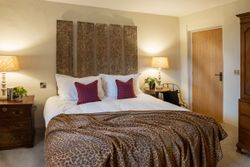 Cozy bedroom with a large bed, animal print blanket, and bedside tables with lamps.