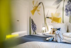 Cozy bedroom with stuffed animals and large floral wallpaper