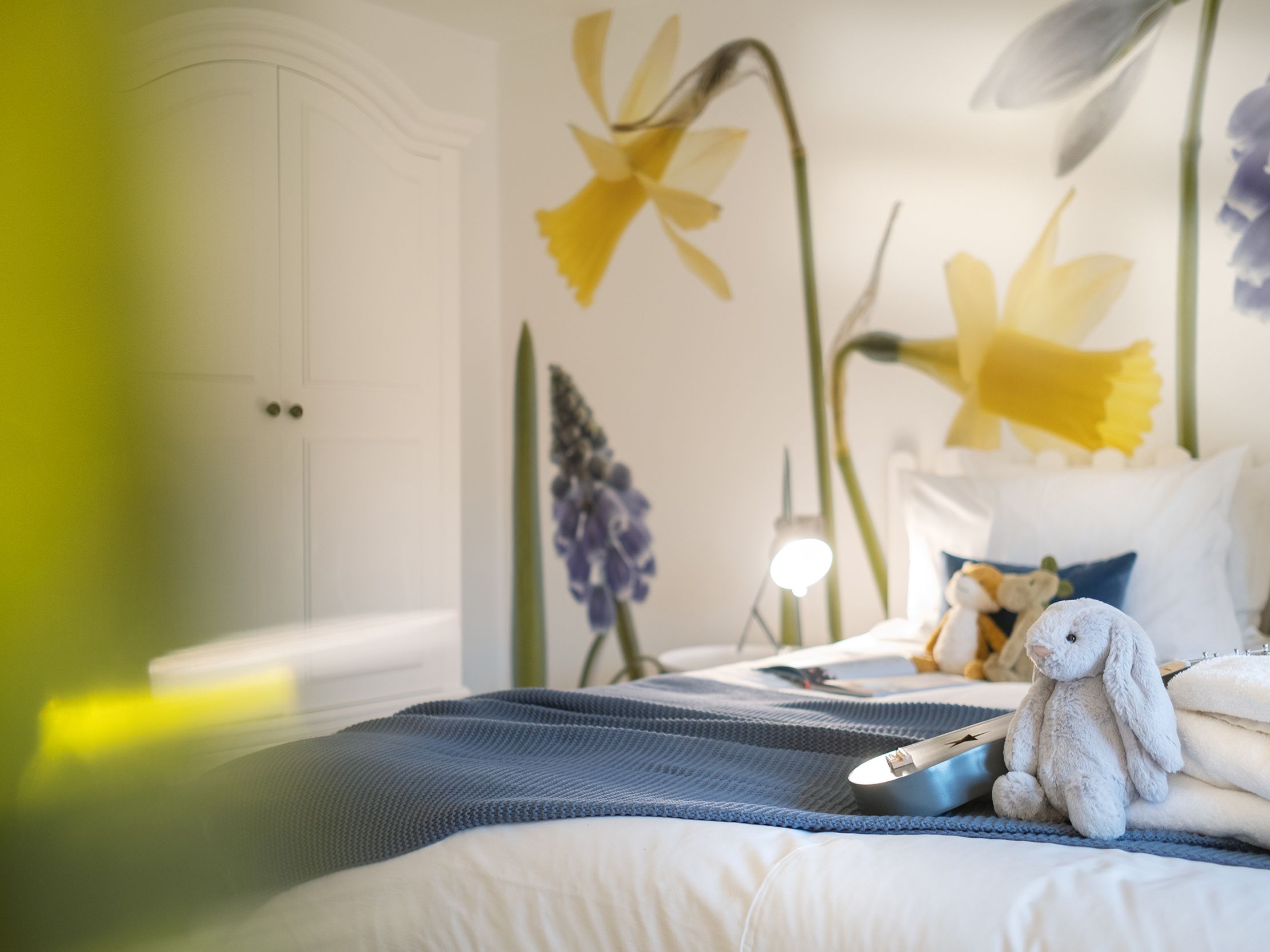 Cozy bedroom with stuffed animals and large floral wallpaper