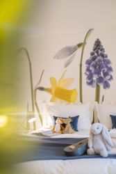 Cozy bed with stuffed animals and floral wall mural