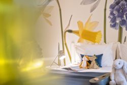 Children's bedroom with large floral mural and stuffed animals on the bed