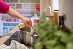 Person stirring a pot on a stove in a kitchen