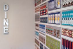 Wall with shelves displaying colorful packaged food products and a vertical sign that spells 'DINE'.