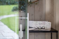 A pair of eyeglasses resting on a folded map with a book on a table next to a potted plant.