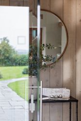 Entryway with a round mirror, console table with a potted plant, map, book, and eyeglasses