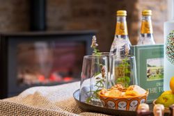 A cozy setup with drinks, snacks, and glasses on a tray in front of a fireplace.