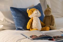 Two stuffed animals on a bed with an open book in front of them