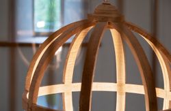 Close-up of a wooden spherical lamp frame with light shining through its slats.