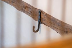 Old metal hook attached to a rustic wooden beam on a wall