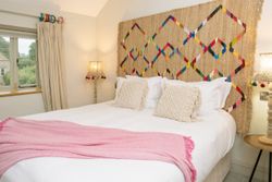 Cozy bedroom with decorative headboard, white bedding, and pink blanket