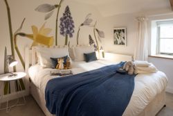 Cozy bedroom with a large bed, plush toys, and floral wall art