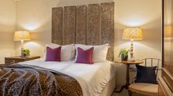 Cozy bedroom with decorative headboard, patterned pillows, and bedside lamps