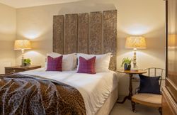 Cozy bedroom with decorative headboard, patterned pillows, and bedside lamps