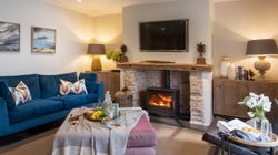 Cozy living room with blue sofa, wood-burning fireplace, and stylish decor