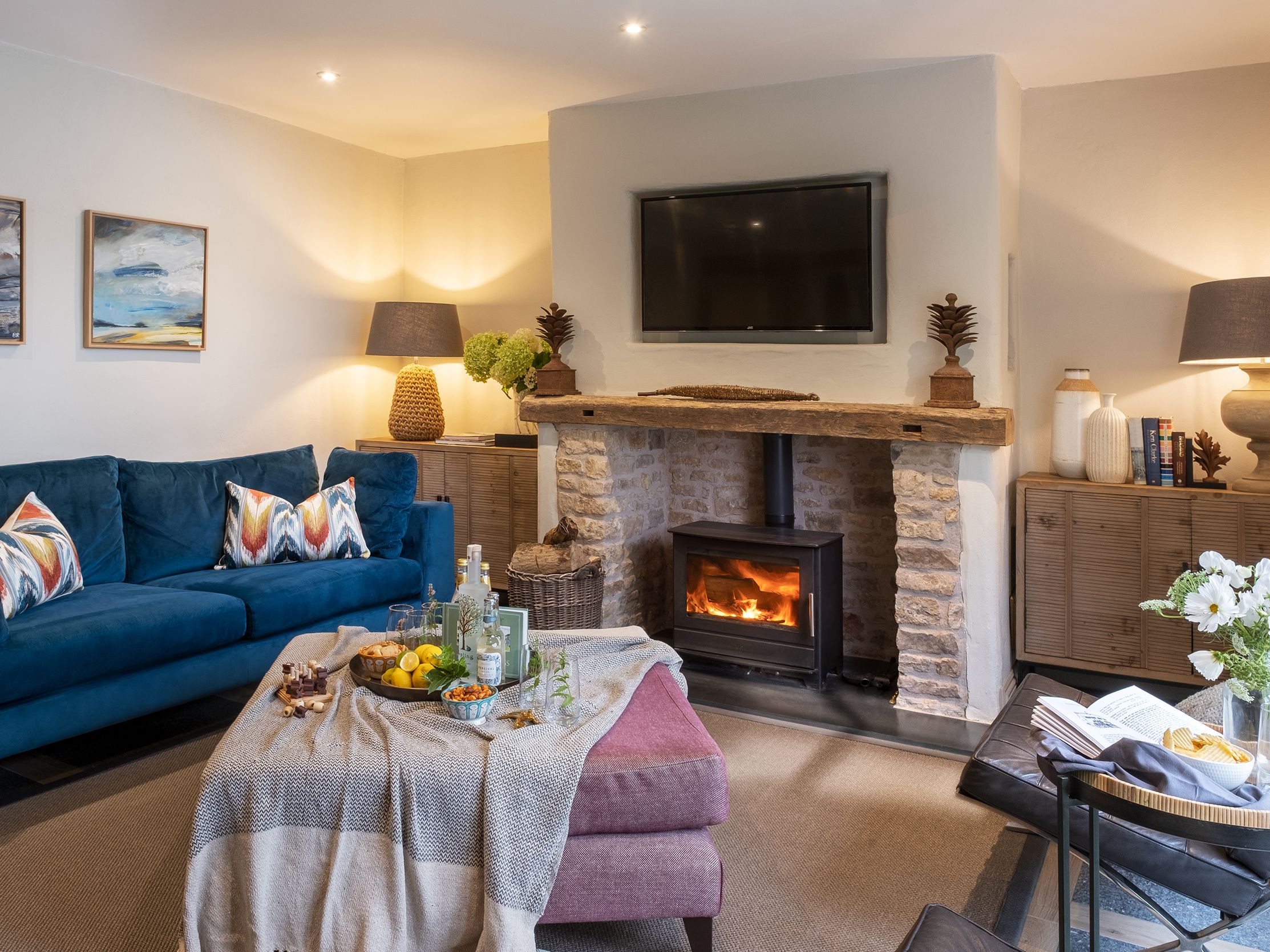Cozy living room with blue sofa, wood-burning fireplace, and stylish decor