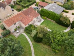 Aerial view of a stone house with a red tile roof and landscaped yard