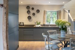 Modern kitchen interior with gray cabinets, wood accents, and a round dining table with flowers