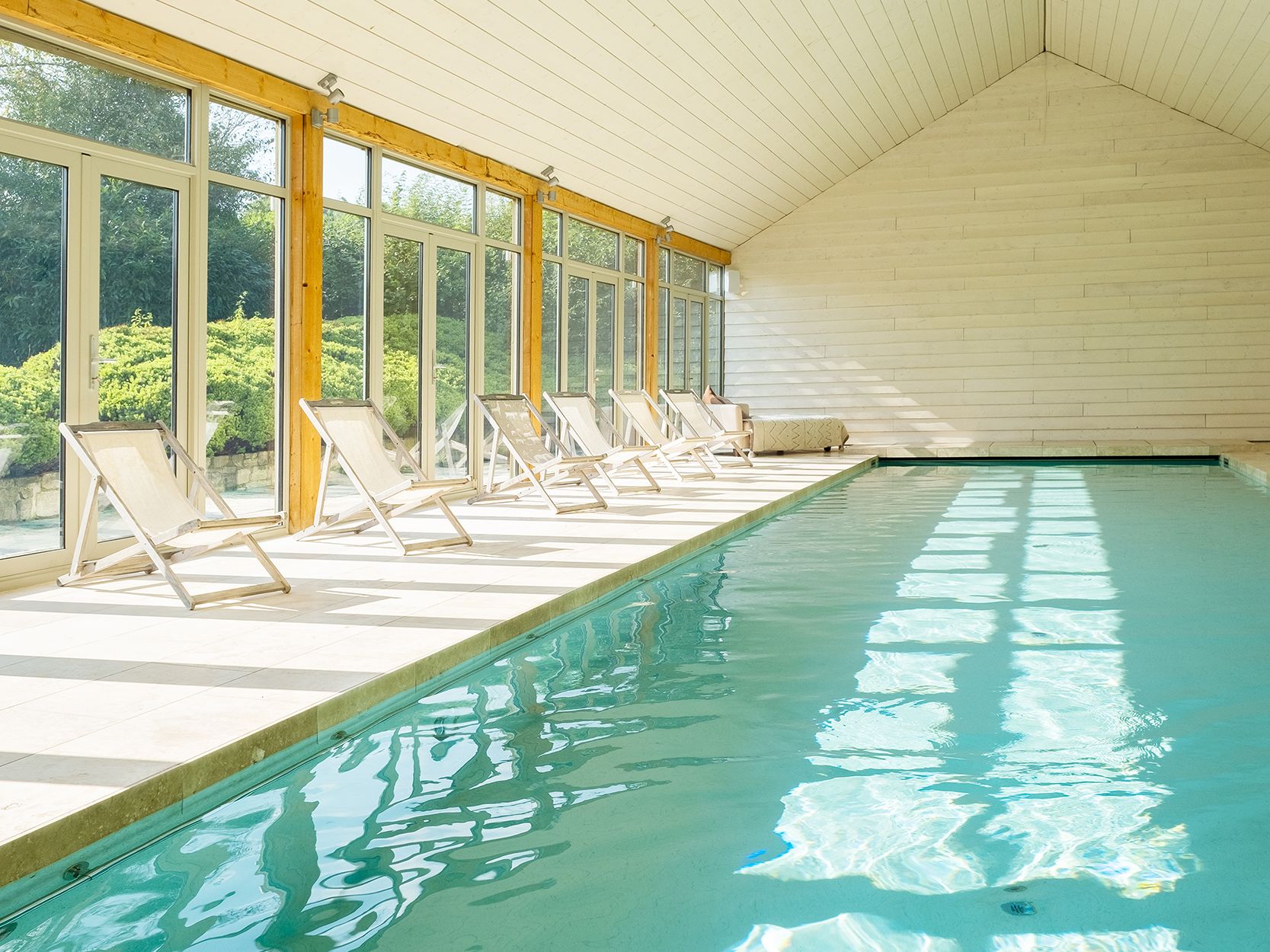 Indoor swimming pool with lounge chairs and large windows