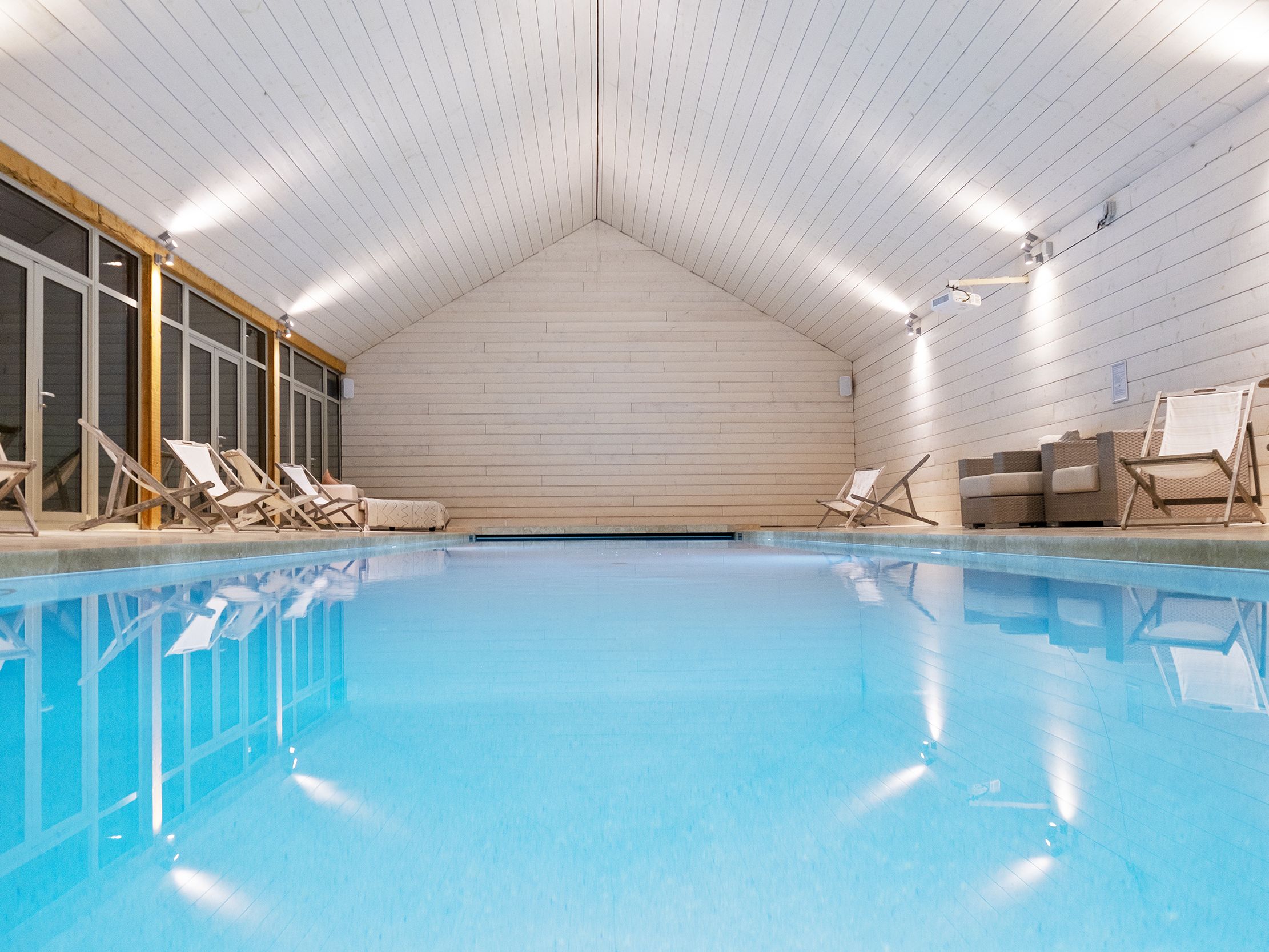Indoor swimming pool with lounge chairs and wooden ceiling