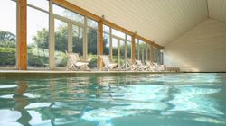 Indoor swimming pool with lounge chairs by large windows