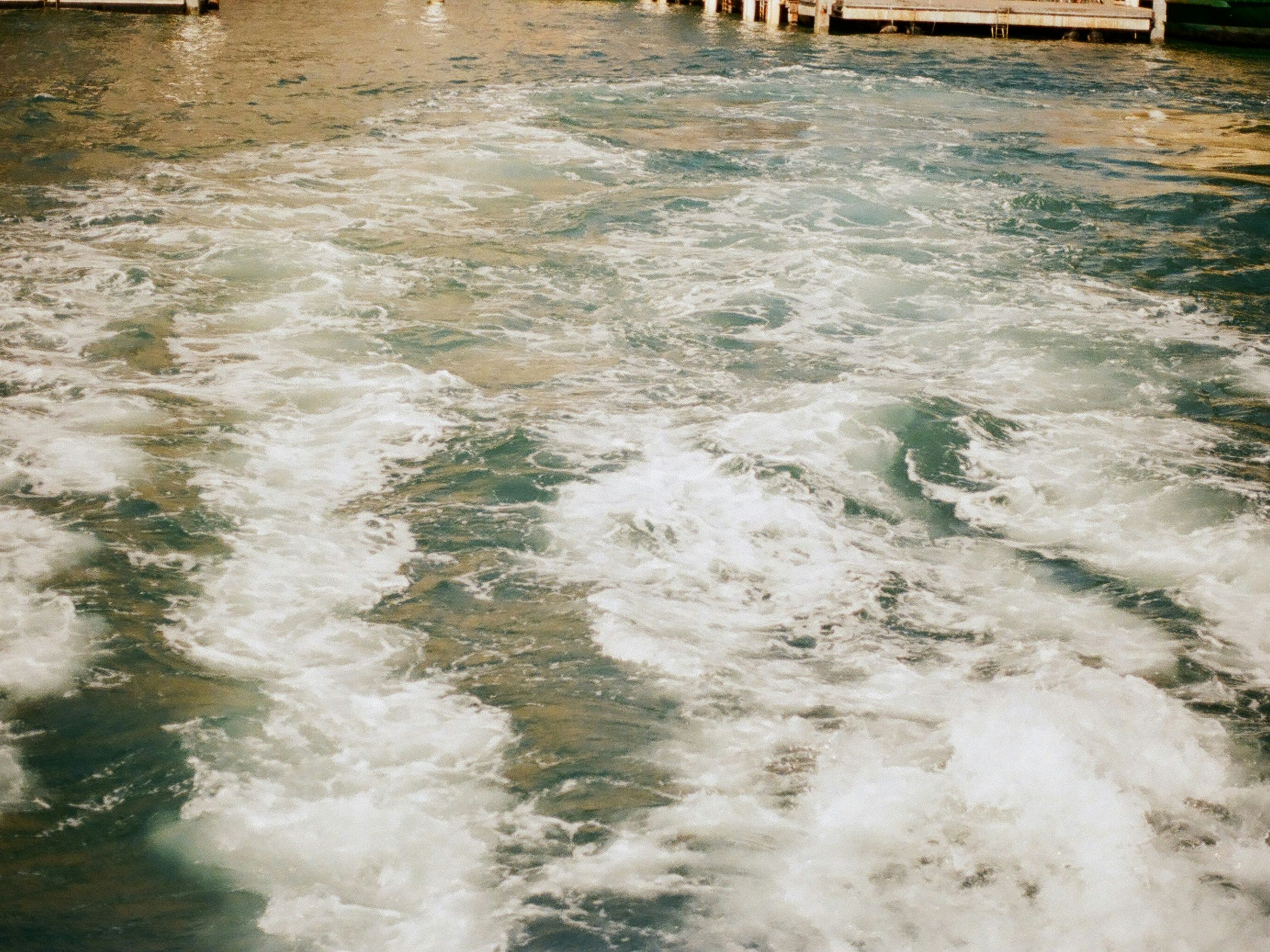 Foamy water with boat wakes and wooden docks in the background