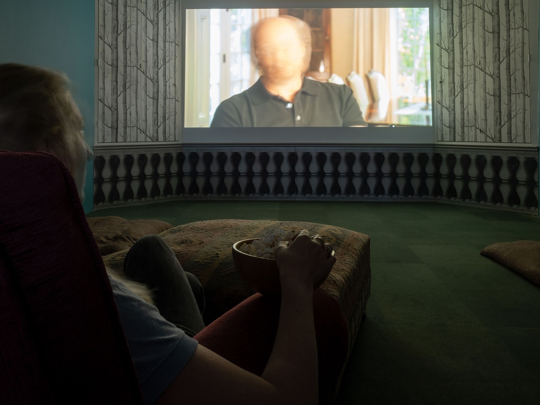 Person sitting in a dark room watching a projected movie with a bowl of popcorn.