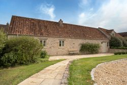 Stone cottage with a tiled roof and garden path in front.