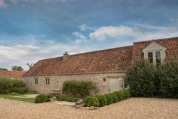 Charming rustic stone cottage with red tiled roof and gravel driveway.
