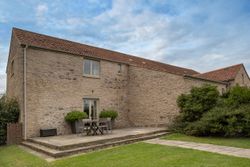 Stone house with a red tile roof, patio, and outdoor table and chairs