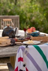 Outdoor table set with food, a teapot, and a striped towel with swimming goggles