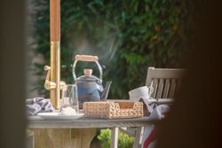 Outdoor table with a teapot, cups, and a basket