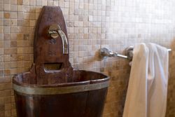 Rustic wooden bathroom sink with a modern metal faucet and towel on the wall