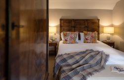 Cozy bedroom with double bed, patterned pillows, lamps, and a blanket