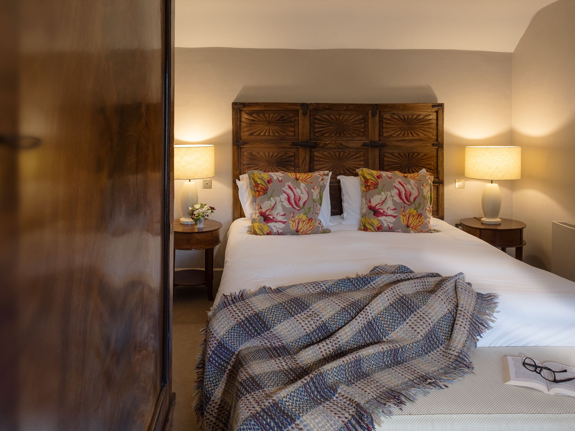 Cozy bedroom with double bed, patterned pillows, lamps, and a blanket