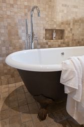 Clawfoot bathtub with chrome faucet and white towel in a tiled bathroom