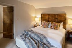 Cozy bedroom with wooden headboard, floral pillows, and soft lighting