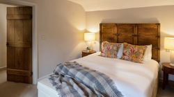 Cozy bedroom with wooden headboard, floral pillows, and soft lighting