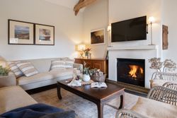 Cozy living room with beige sofas, a wooden coffee table, a fireplace, and wall art.