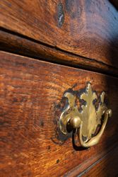 Close-up of a brass drawer handle on an antique wooden dresser