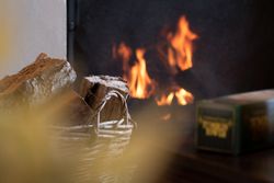 Close-up of firewood in a wicker basket with a fireplace burning in the background
