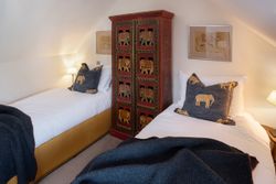 Bedroom with two single beds, elephant-themed pillows, and a decorative wardrobe