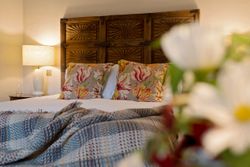 Cozy bedroom with floral pillows, wooden headboard, and bedside lamp