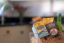 Gift basket with Miles tea, West Country Legends snacks, and other treats on a kitchen counter.