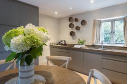 Modern kitchen with gray cabinets, a vase of white and green hydrangeas on the table, and circular wall decor.