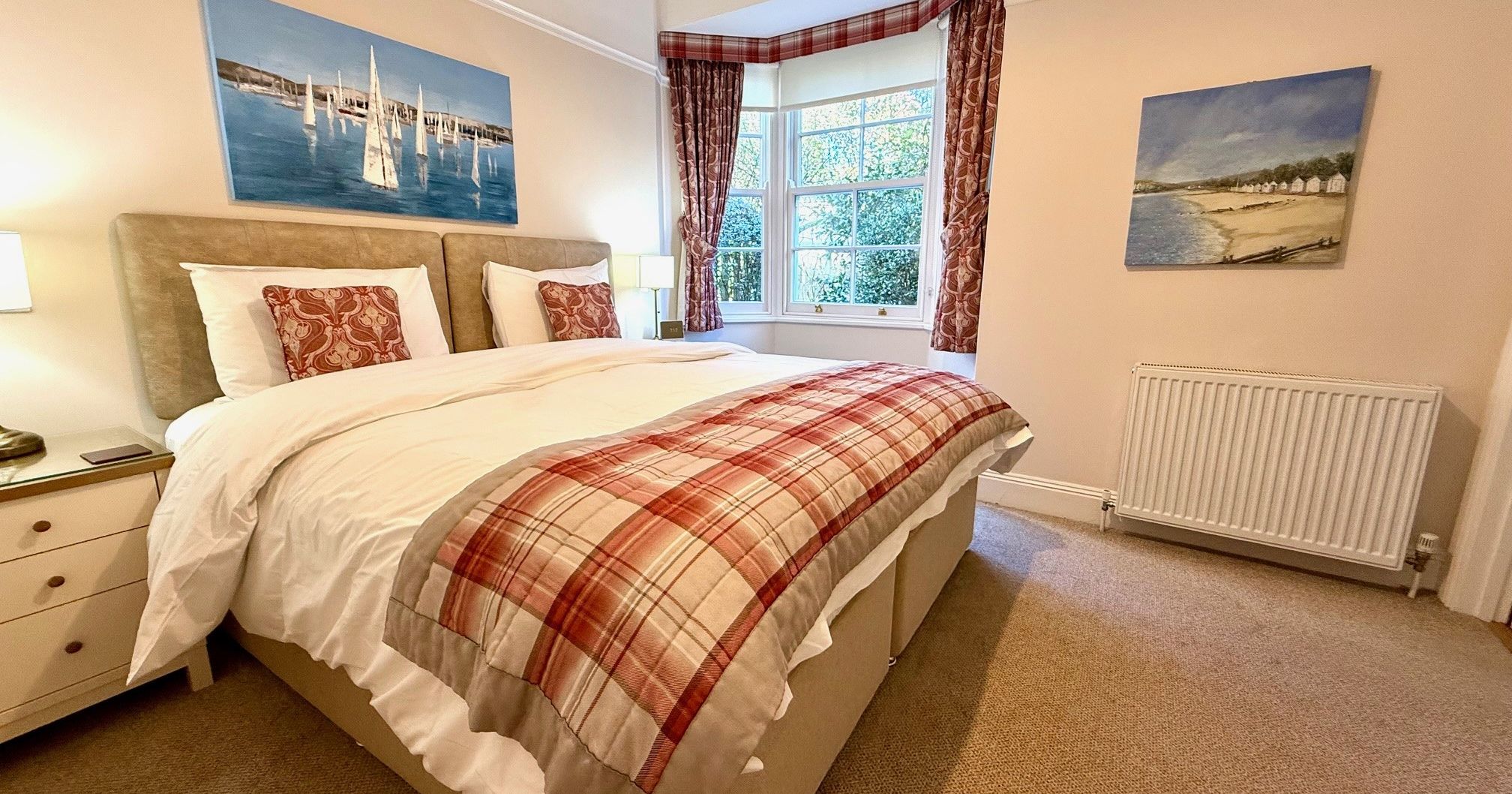 Ground floor bedroom with double bed, plaid throw and bay window